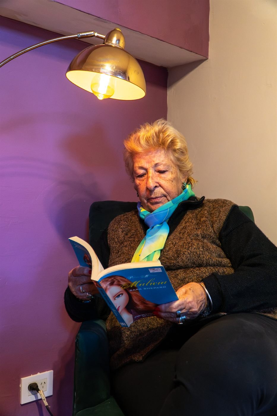 Una residente lee un libro junto a la lámpara de su habitación.
