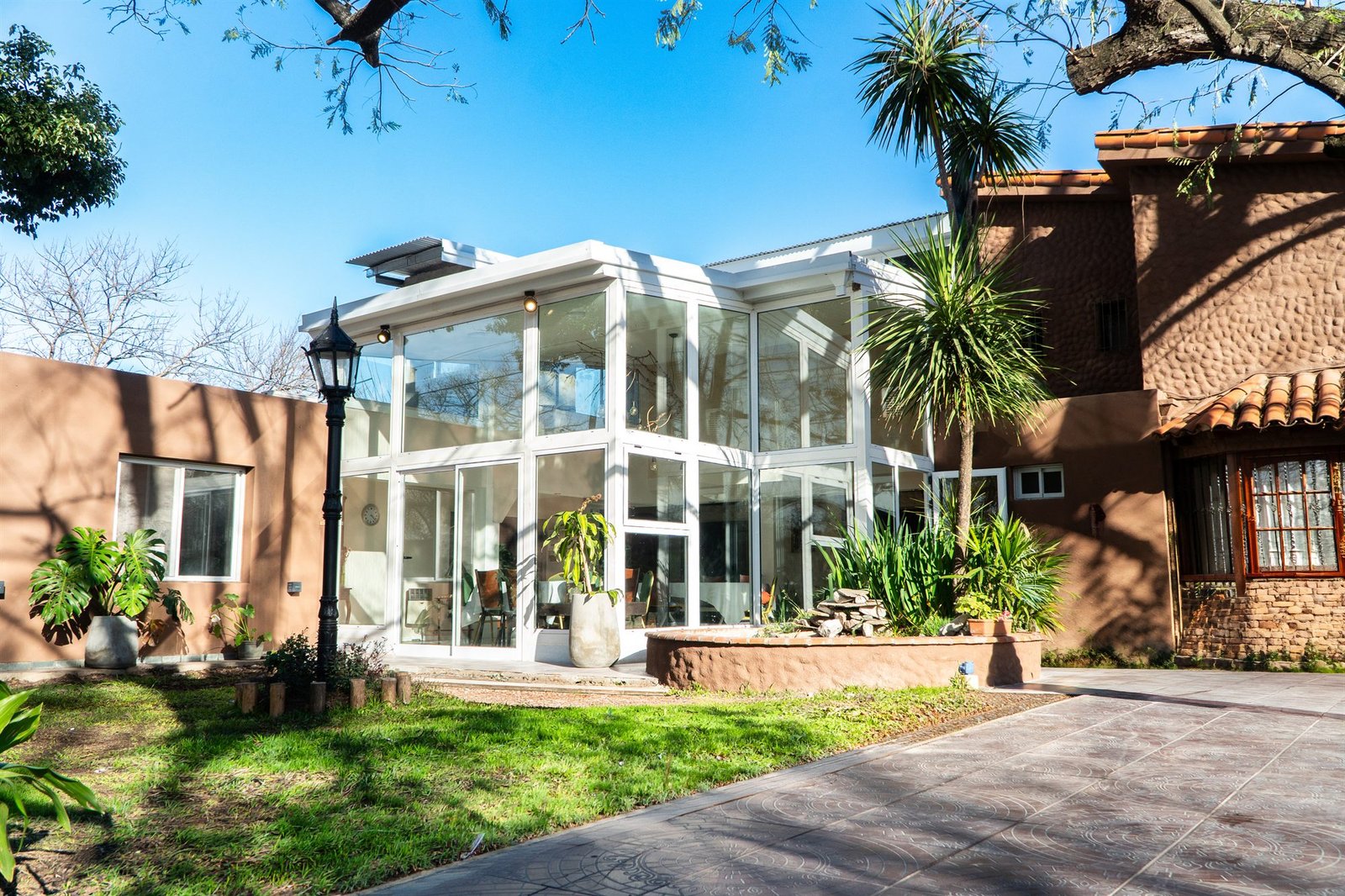 La galería vidriada de Alcanfor abierta al jardín, con luz natural.
