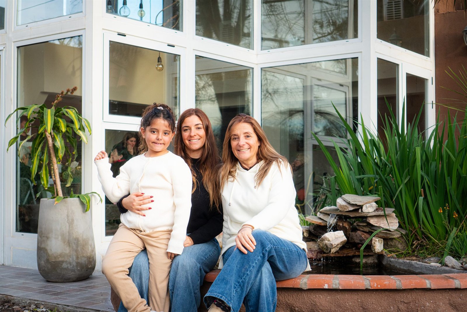 Tres generaciones de una familia comparten un momento en el jardín de Alcanfor.
