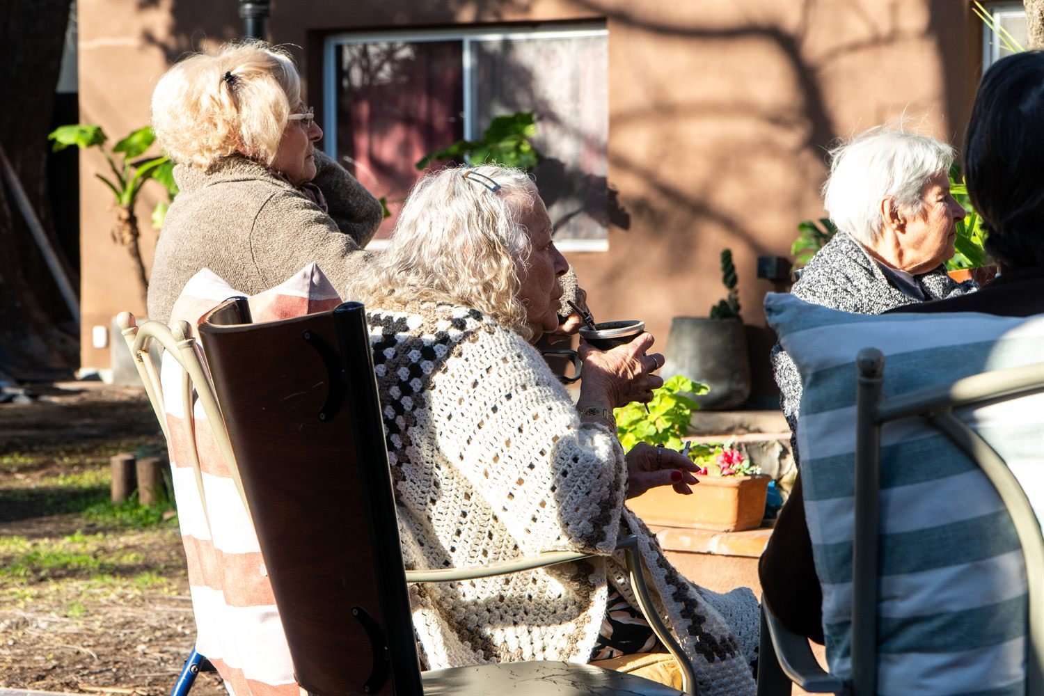Dos residentes conversan al sol en el jardín.